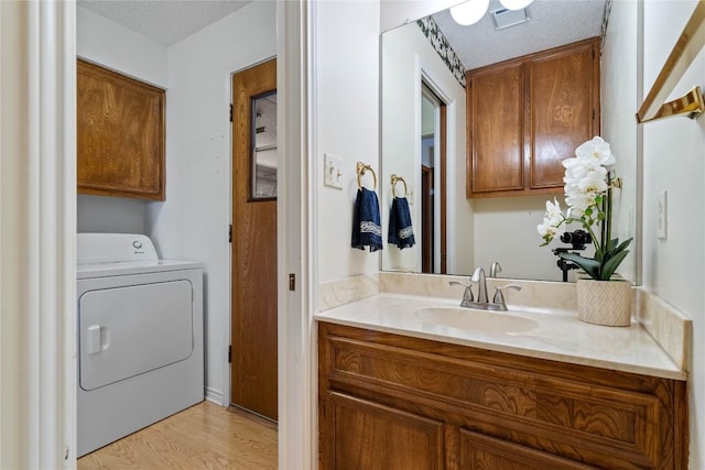21407 High Dr, Lago Vista, TX 78645 - bathroom featuring washer / dryer, vanity, wood finished floors, and a textured ceiling