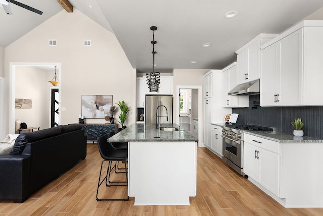 347 Stars And Stripes, Fischer, TX 78623 - kitchen featuring stainless steel appliances, under cabinet range hood, open floor plan, beam ceiling, and dark stone counters