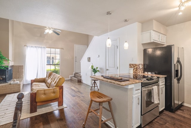 5604 Woodrow Ave Unit 7, Austin, TX 78756 - kitchen with appliances with stainless steel finishes, dark wood-style flooring, white cabinetry, ceiling fan, and a kitchen bar