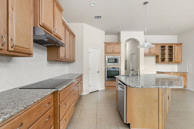 217 Monahans Dr, Georgetown, TX 78628 - kitchen featuring under cabinet range hood, appliances with stainless steel finishes, decorative backsplash, light stone countertops, and light tile patterned floors