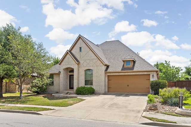217 Monahans Dr, Georgetown, TX 78628 - french country inspired facade with brick siding, driveway, an attached garage, and a shingled roof