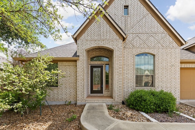 217 Monahans Dr, Georgetown, TX 78628 - property entrance with brick siding, an attached garage, and roof with shingles