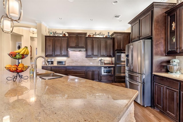 2560 Square Nail Cv, Leander, TX 78641 - kitchen featuring stainless steel appliances, a sink, light stone countertops, dark brown cabinetry, and decorative backsplash