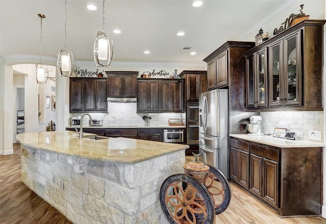 2560 Square Nail Cv, Leander, TX 78641 - kitchen with appliances with stainless steel finishes, dark brown cabinets, light stone countertops, decorative backsplash, and crown molding