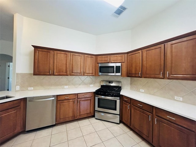 kitchen with decorative backsplash, stainless steel appliances, visible vents, and light countertops