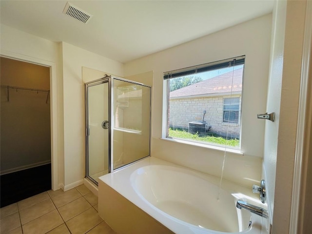 bathroom with tile patterned floors, a stall shower, a walk in closet, a bath, and visible vents