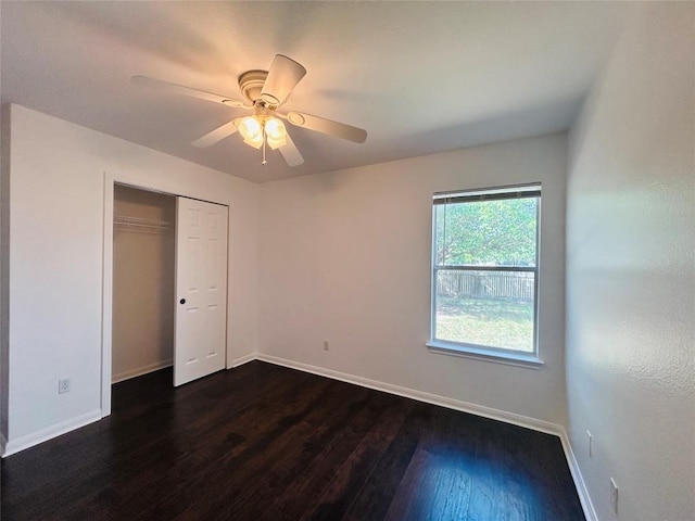 unfurnished bedroom with baseboards, a closet, a ceiling fan, and dark wood-style floors