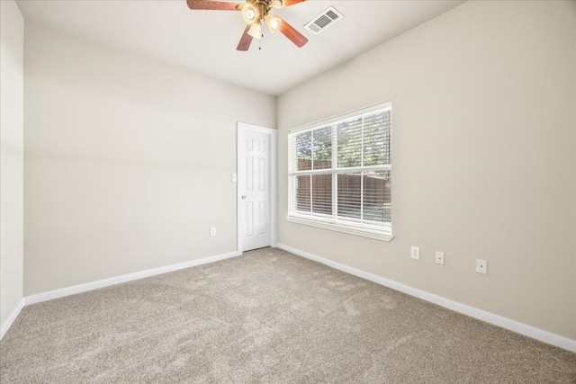 carpeted spare room with visible vents, a ceiling fan, and baseboards