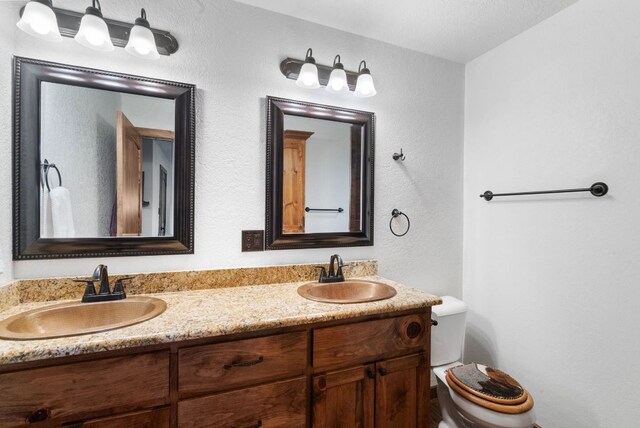 full bath with double vanity, toilet, and a sink
