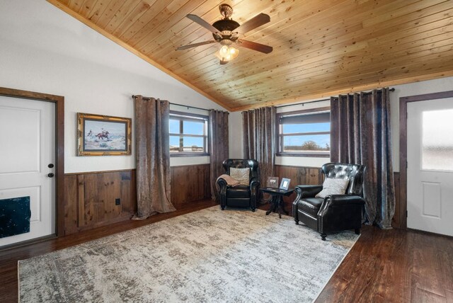 sitting room with vaulted ceiling, wood finished floors, ceiling fan, a wainscoted wall, and wooden ceiling