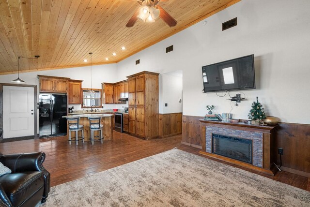 living room featuring wainscoting, vaulted ceiling, visible vents, a ceiling fan, and wood ceiling