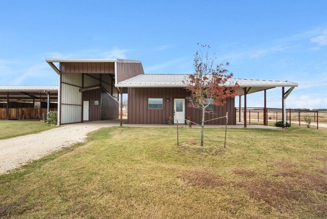 exterior space featuring an exterior structure, an outbuilding, driveway, metal roof, and board and batten siding