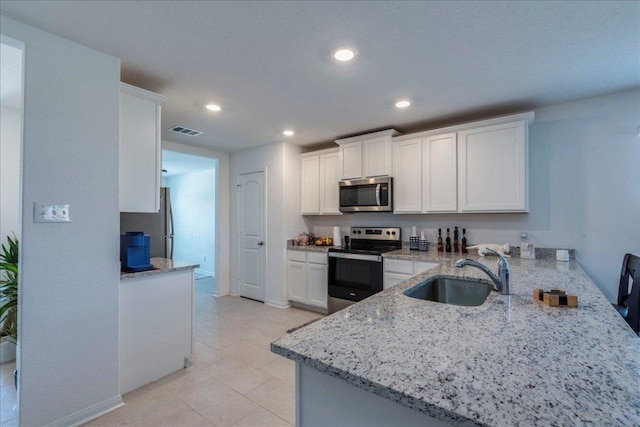 17216 Farmhouse Ln, Elgin, TX 78621 - kitchen featuring stainless steel appliances, a sink, white cabinetry, light stone counters, and recessed lighting