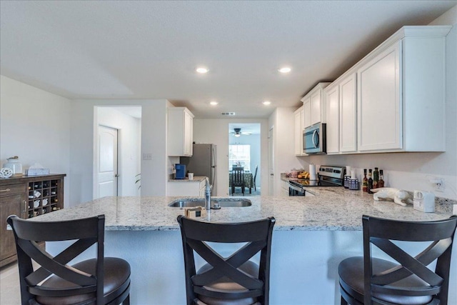 17216 Farmhouse Ln, Elgin, TX 78621 - kitchen with appliances with stainless steel finishes, a sink, light stone counters, white cabinetry, and recessed lighting