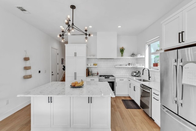 4614 Gillis St Unit 1, Austin, TX 78745 - kitchen with appliances with stainless steel finishes, open shelves, wall chimney exhaust hood, a sink, and a kitchen island