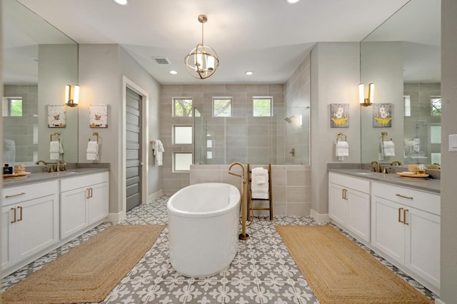 125 Reataway Dr, Dripping Springs, TX 78620 - bathroom featuring tiled shower, two vanities, a freestanding tub, healthy amount of natural light, and recessed lighting