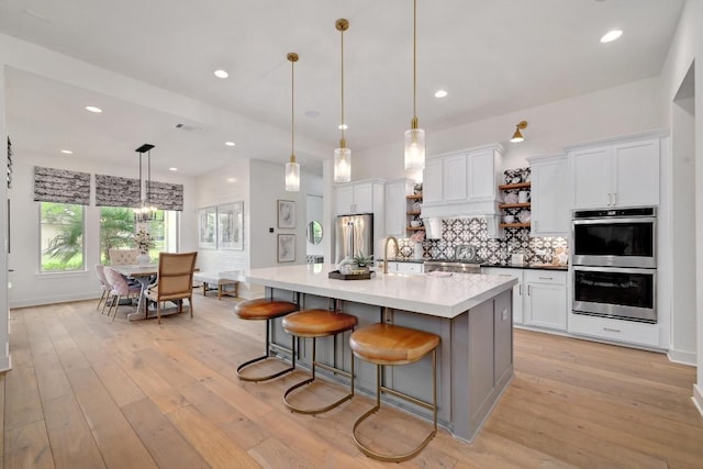 125 Reataway Dr, Dripping Springs, TX 78620 - kitchen with appliances with stainless steel finishes, white cabinets, a sink, tasteful backsplash, and light wood finished floors