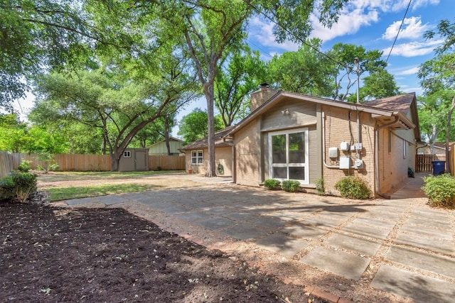 4807 Gerona Dr, Austin, TX 78759 - rear view of house featuring brick siding, a storage shed, a patio, a chimney, and a fenced backyard