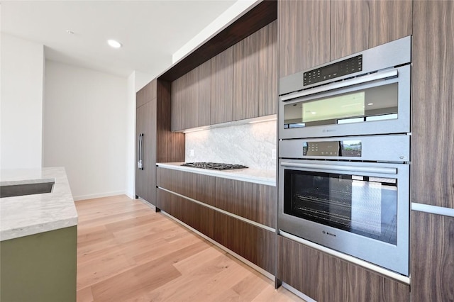 2209 S 1st St Unit 408, Austin, TX 78704 - kitchen featuring stainless steel double oven, light countertops, backsplash, light wood-type flooring, and recessed lighting