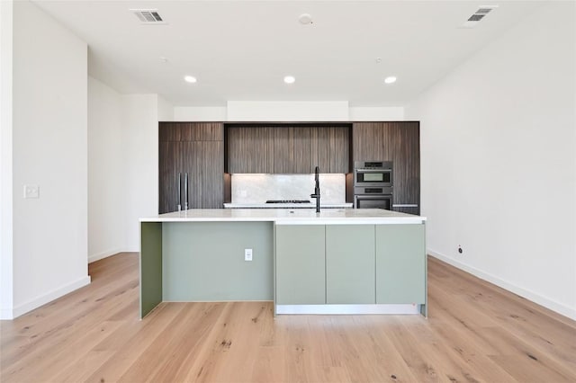 2209 S 1st St Unit 408, Austin, TX 78704 - kitchen with a kitchen island with sink, light countertops, double oven, modern cabinets, and baseboards