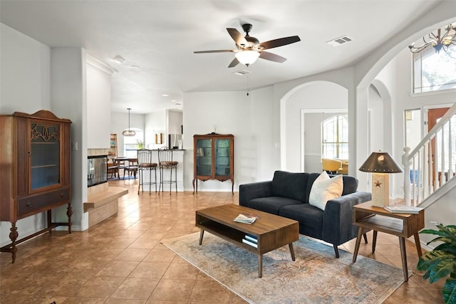 living area with light tile patterned flooring, arched walkways, visible vents, and ceiling fan