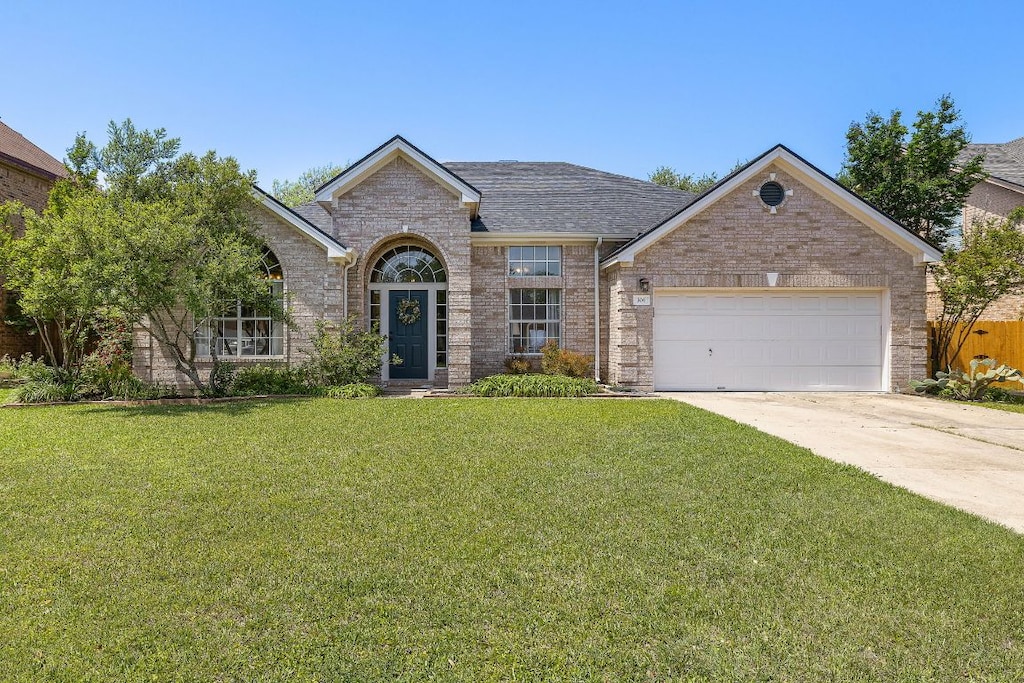 306 Steeplechase Dr, Georgetown, TX 78626 - view of front facade featuring a front lawn, driveway, brick siding, a garage, and a shingled roof