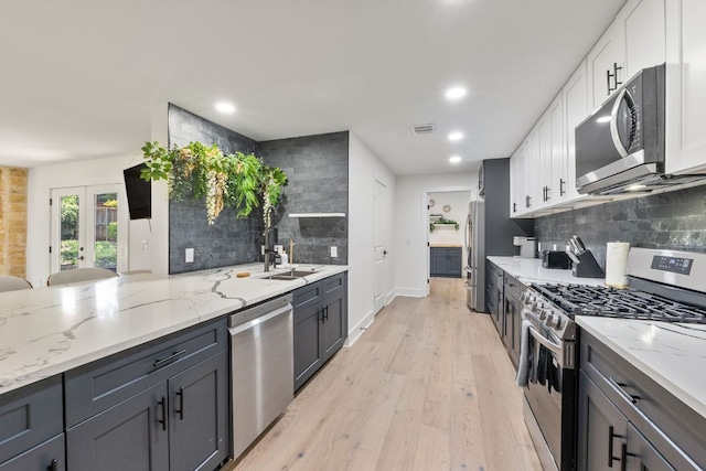 5800 Marilyn Dr, Austin, TX 78757 - kitchen featuring appliances with stainless steel finishes, backsplash, white cabinetry, light stone counters, and recessed lighting