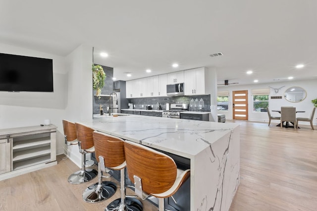 5800 Marilyn Dr, Austin, TX 78757 - kitchen with stainless steel appliances, light wood-style floors, a peninsula, backsplash, and white cabinetry