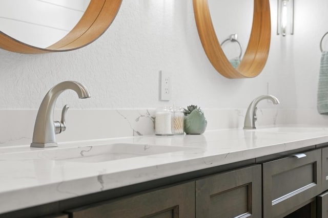 full bath featuring a textured wall, a sink, and double vanity