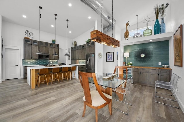 dining room with light wood-style flooring, a towering ceiling, and recessed lighting