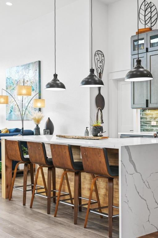 bar with decorative light fixtures, decorative backsplash, and light wood-type flooring
