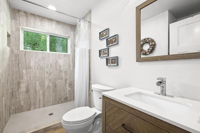 bathroom featuring a tile shower, toilet, and vanity
