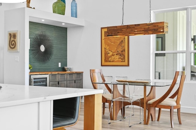 kitchen featuring light wood-style flooring, baseboards, beverage cooler, and light stone counters