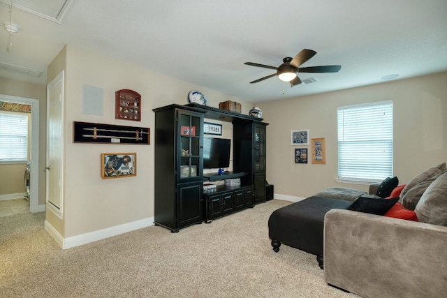 living area featuring attic access, ceiling fan, light carpet, and a healthy amount of sunlight