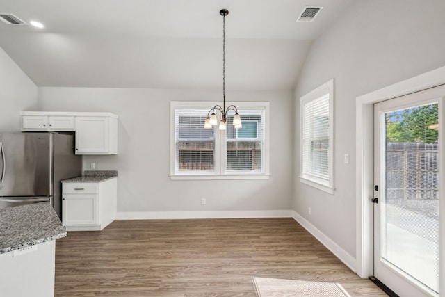206 N Winston Dr, Fredericksburg, TX 78624 - unfurnished dining area with a chandelier, lofted ceiling, visible vents, and light wood finished floors