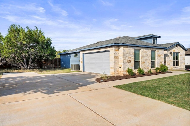 view of front of home featuring stone siding, driveway, a garage, central AC unit, and roof with shingles