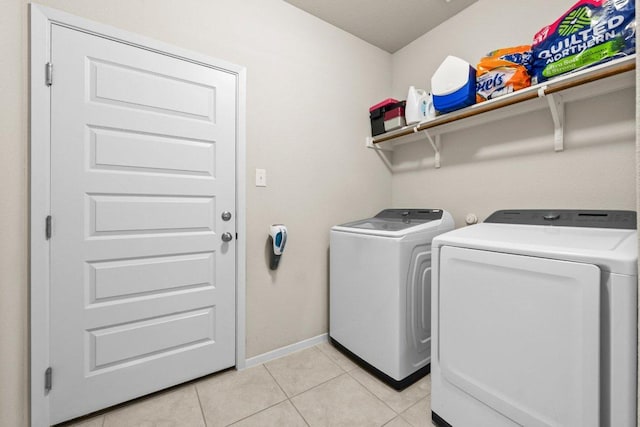 washroom featuring separate washer and dryer, light tile patterned floors, and baseboards
