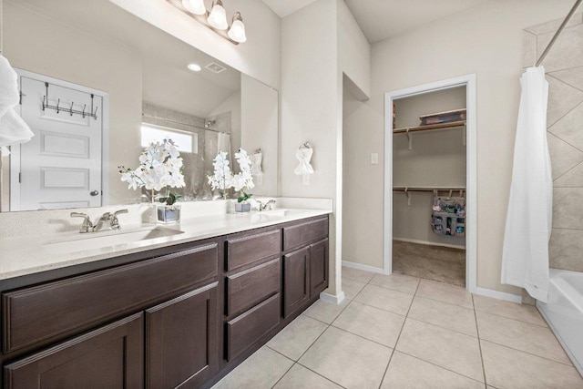 full bathroom with double vanity, a walk in closet, tile patterned flooring, and baseboards