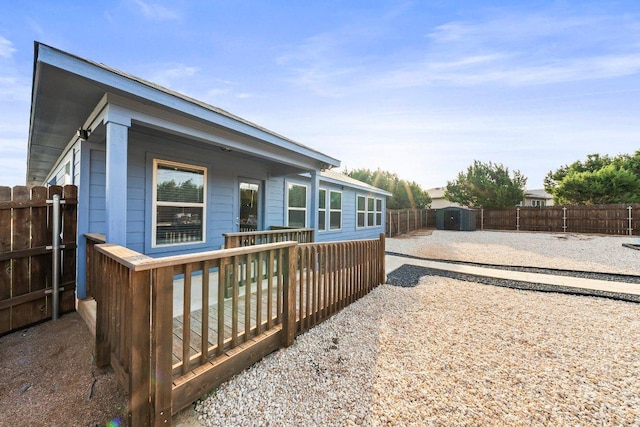 rear view of property with a fenced backyard, a storage unit, and an outdoor structure