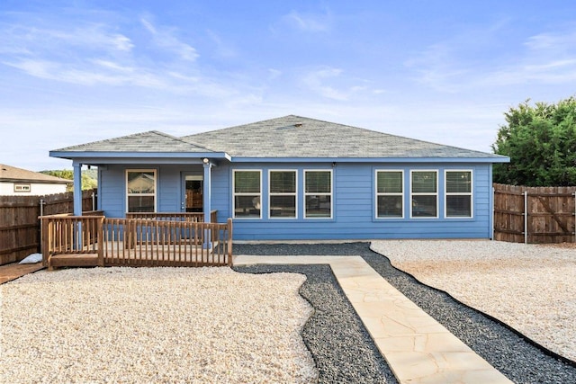 rear view of house featuring fence, a shingled roof, and covered porch