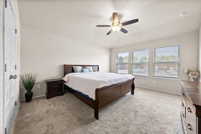bedroom with baseboards, light colored carpet, vaulted ceiling, and ceiling fan
