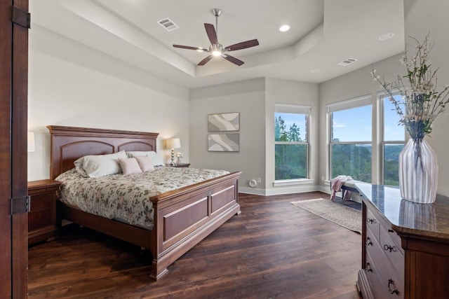 bedroom featuring baseboards, visible vents, a raised ceiling, and dark wood-style flooring