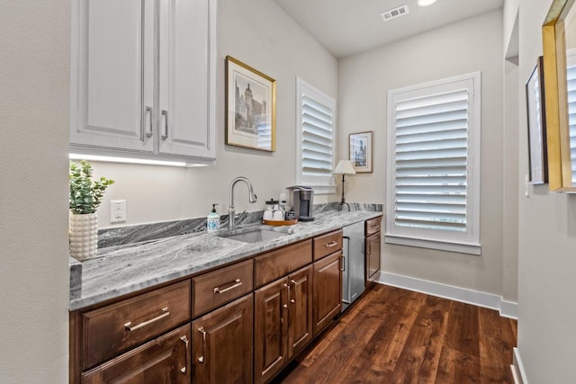 interior space featuring baseboards, visible vents, dark wood-style floors, and a sink