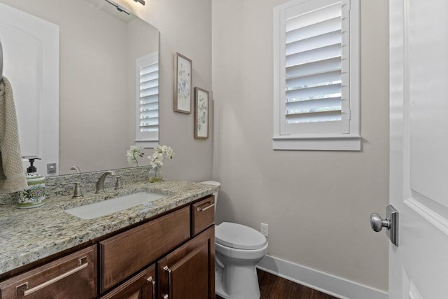 bathroom featuring baseboards, toilet, vanity, and wood finished floors