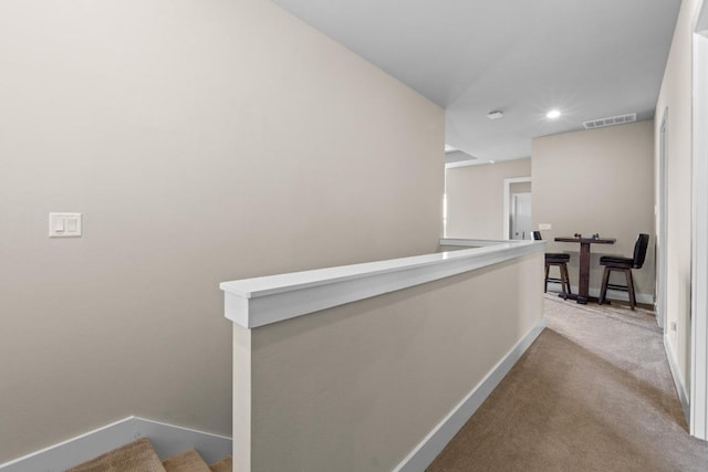 hallway with carpet flooring, baseboards, visible vents, recessed lighting, and an upstairs landing