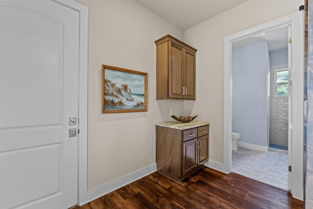 corridor featuring baseboards and dark wood-type flooring