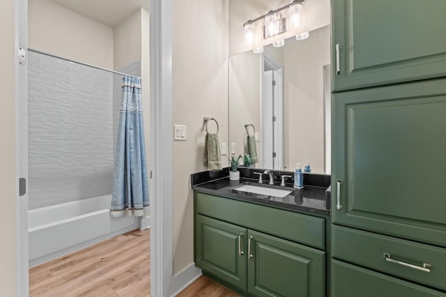 bathroom featuring baseboards, vanity, wood finished floors, and shower / bath combo with shower curtain