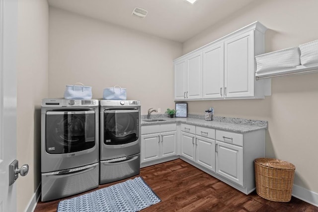 laundry area featuring visible vents, a sink, washing machine and dryer, dark wood-type flooring, and cabinet space