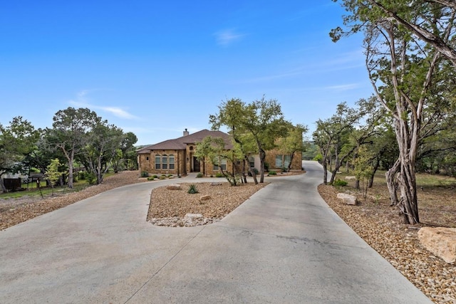view of front of house with a chimney and curved driveway