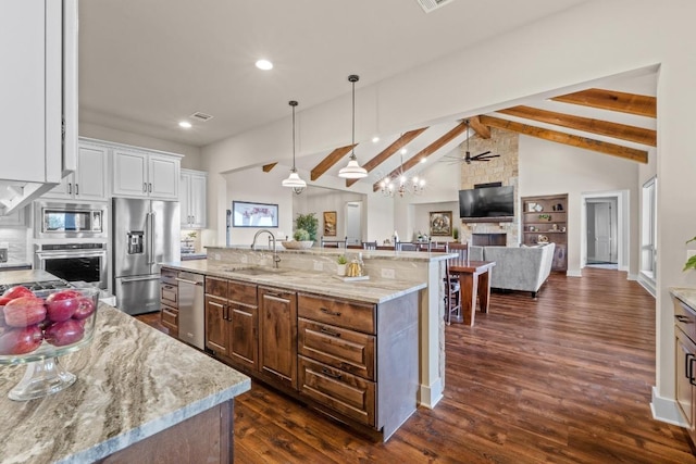 kitchen featuring lofted ceiling with beams, stainless steel appliances, a kitchen island with sink, a sink, and ceiling fan